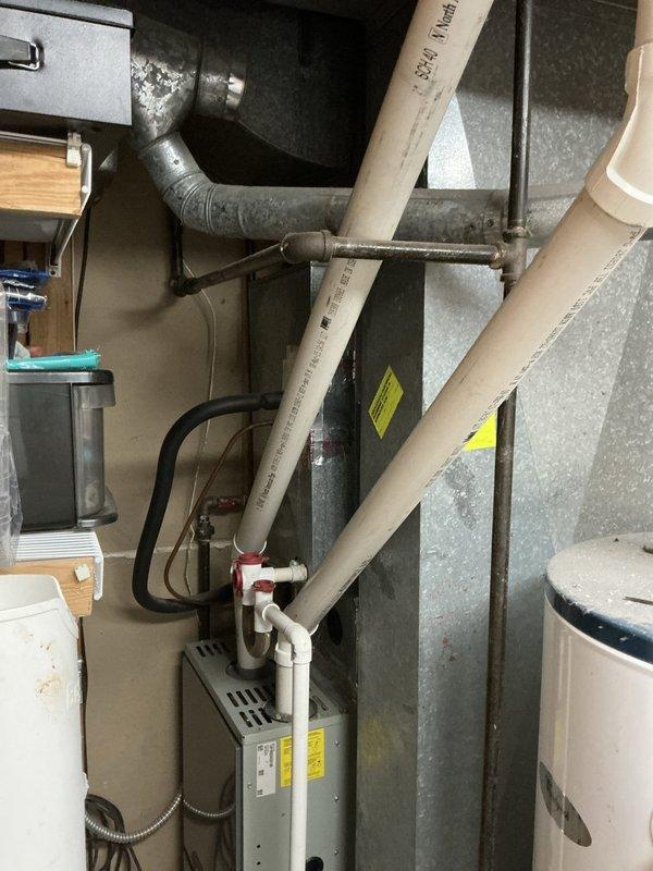 Responded to service call for 16-year-old residential air conditioning system blowing lukewarm air with inadequate cooling performance. Conducted comprehensive system evaluation including inspection of outdoor condenser unit and indoor air handler components in utility room. Documented existing equipment configuration and mechanical space layout showing HVAC ductwork, humidifier accessory, and associated plumbing connections. Prepared estimate for necessary repairs to restore proper cooling function to the system.