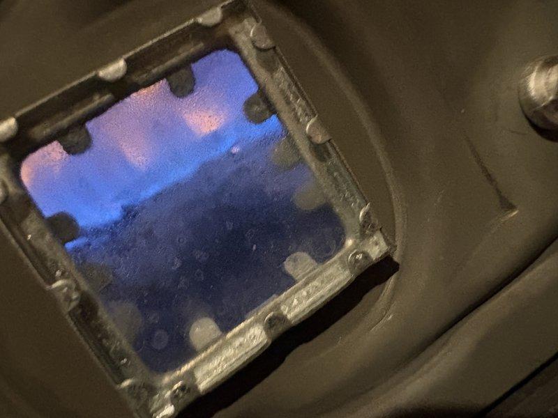 Responded to service call for 19-year-old water heater with no hot water production and pilot light failure. Upon inspection, successfully relit pilot light and verified proper burner ignition, as evidenced by blue flame visible through viewing window. Tested unit operation and confirmed restoration of hot water supply to residence.
