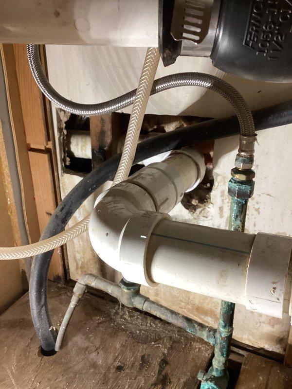 Responded to reported leak in wall. Removed section of drywall to access plumbing behind kitchen sink cabinet. Upon inspection, identified corrosion and oxidation on copper supply fittings and connections beneath sink, with visible water staining on cabinet floor indicating previous moisture intrusion. Documented existing plumbing conditions including garbage disposal installation, PVC drain assembly, braided supply lines, and corroded shut-off valves with green handles. Inspected outdoor spigot as requested and verified operational status. Secured all accessible plumbing connections and advised on condition of aging fixtures showing significant wear and corrosion requiring future attention.