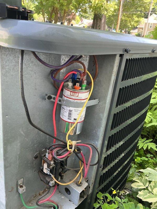 # CP-Cooling Problem Service Completion

Responded to service call for 15-year-old air conditioning system experiencing excessive noise and inability to maintain consistent temperature setpoint. Upon arrival, performed diagnostic evaluation of outdoor condensing unit. Removed access panel to inspect electrical components and internal systems. 

Visual inspection revealed aged electrical components including capacitor and contactor assembly. Examined all wire connections at capacitor terminals, noting multiple colored conductors (red, yellow, purple, brown, green) secured to top terminals. Inspected contactor relay unit positioned below capacitor, verifying connection integrity of associated wiring. Assessed condition of condenser coil fins, which showed normal weathering consistent with outdoor equipment age.

Evaluated overall system operation and component functionality. Documented existing conditions through photographic records showing capacitor, contactor, wiring configuration, an