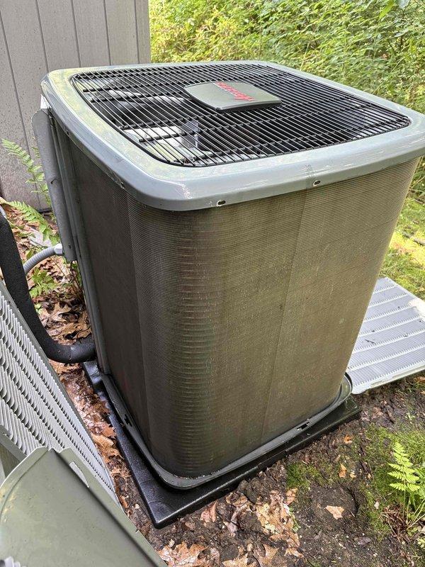 Responded to complaint of excessive cooling in basement zone causing severe condensation and water pooling on carpets and baseboards in 3-zone system. Upon arrival, inspected 8-year-old Carrier system and found outdoor condenser unit with significant biological growth and deteriorated protective coverings indicating prolonged moisture exposure and lack of maintenance. Documented exterior unit condition showing extensive mold/mildew accumulation on cabinet panels and damaged insulation materials with exposed mesh components. Issue likely caused by stuck or malfunctioning zone damper in basement supply duct allowing continuous cold air flow, combined with inadequate humidity control. Photographed equipment deterioration and moisture damage for service records. Recommended immediate zone damper inspection/replacement, humidity level assessment, and evaluation of basement return air configuration to resolve overcooling condition and prevent further water damage to finished surfaces.