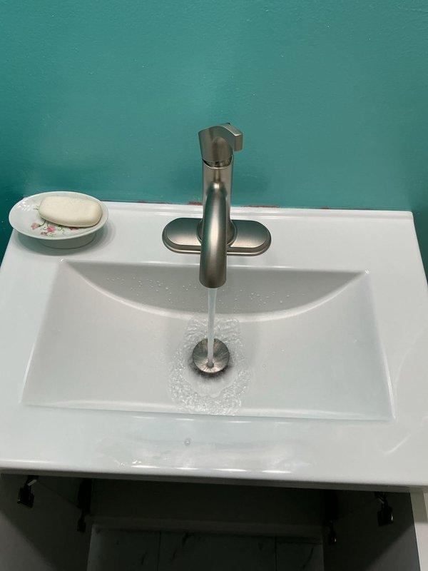 Completed installation and testing of bathroom sink plumbing system, including PVC drain assembly and brushed stainless steel single-lever faucet. Verified proper water flow, drainage function, and confirmed no leaks in cabinet connections beneath vessel sink.