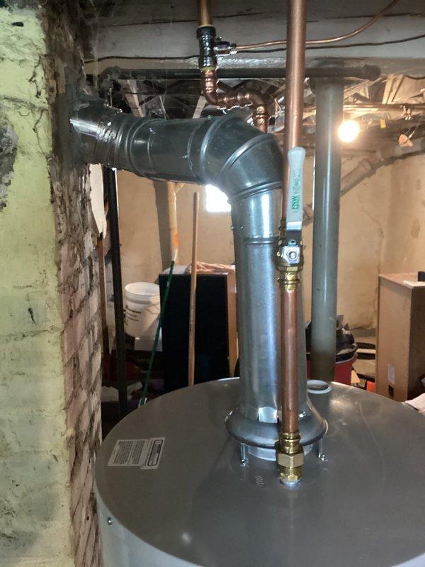 Responded to emergency call for leaking water heater in residential basement. Upon inspection, found 15-year-old 40-gallon water heater actively leaking and requiring immediate replacement. Unit had reached end of serviceable life with visible deterioration. Documented existing installation configuration including copper supply lines, PVC venting system, and proximity to furnace unit in mechanical room. Photographed current setup showing water heater connections, surrounding plumbing infrastructure, and basement utility area layout to facilitate replacement planning. Provided estimate for complete water heater replacement to restore hot water service.
