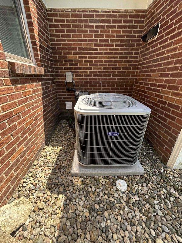 Completed full air conditioning system replacement at residential property. Removed existing unit and installed new Carrier condenser in exterior brick alcove with proper clearance for airflow and serviceability. Mounted unit on concrete pad with river rock drainage bed for water management. Installed associated electrical components including disconnect box, conduit runs, and proper wiring connections per manufacturer specifications and local code requirements. Verified refrigerant lines, condensate drainage, and all electrical connections. System tested and confirmed operational with proper cooling performance.