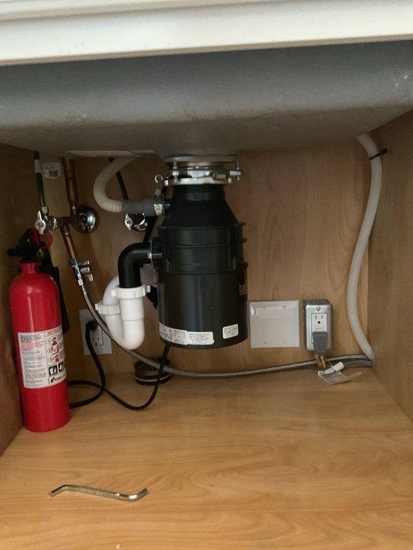 Responded to mother-in-law suite for garbage disposal seizing and leak under sink. Upon inspection, found disposal unit jamming and minor leak at mounting assembly. Freed impeller jam, tested disposal operation, and tightened mounting flange to eliminate leak. Verified proper drainage through P-trap configuration and confirmed all connections secure with no active leaks. Unit restored to full operational status.