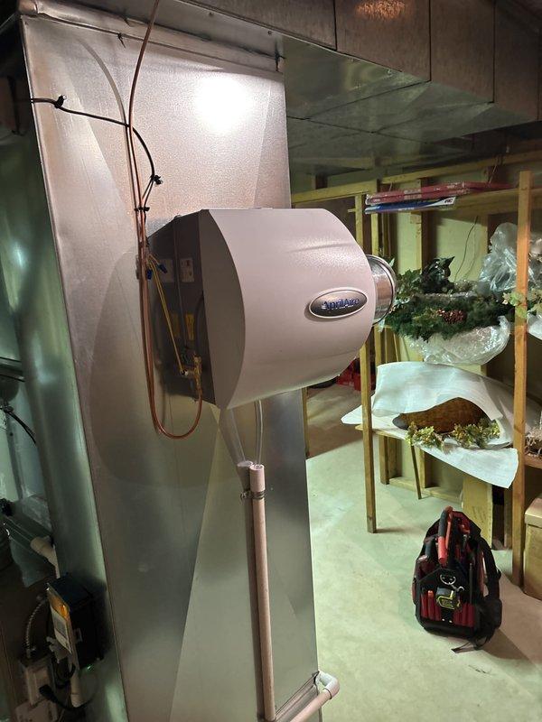 Completed full installation of new furnace and air conditioning system in basement utility area. Installed furnace unit with proper venting, including copper exhaust piping with 90-degree elbow configuration routed through ceiling. Mounted and integrated humidifier unit to HVAC system with copper feed line and electrical connections. Installed wall-mounted thermostat control with illuminated display. All electrical wiring, conduit, and connections completed per code. System tested and verified operational upon completion.