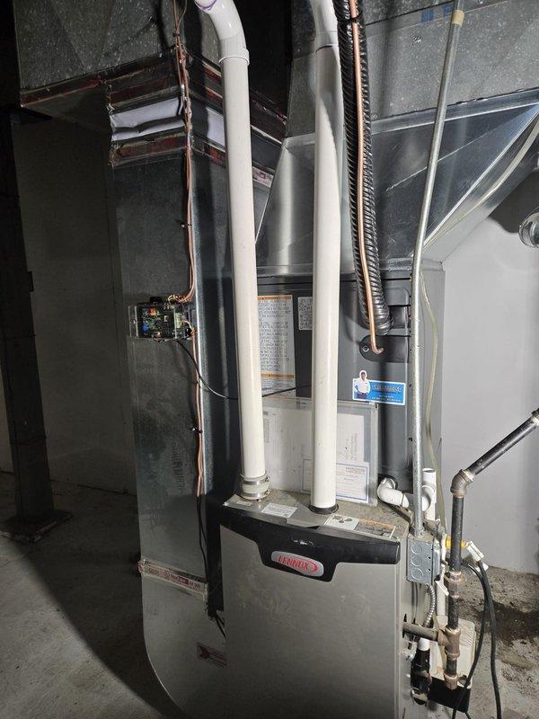 Completed full HVAC system replacement in basement mechanical room. Removed existing equipment and installed new Lennox furnace with vertical air handler configuration. Ran white PVC venting pipes from furnace unit through ceiling for proper exhaust and intake ventilation. Connected copper refrigerant lines between units with appropriate insulation wrapping. Installed rectangular sheet metal ductwork and insulated flexible ducting to distribute conditioned air throughout residence. Performed all electrical connections including conduit and junction box mounting to concrete block walls. Routed copper and PEX plumbing lines as needed for system operation. Verified all manufacturer specifications, safety placards, and labeling were properly displayed on equipment. System tested and operational upon completion.
