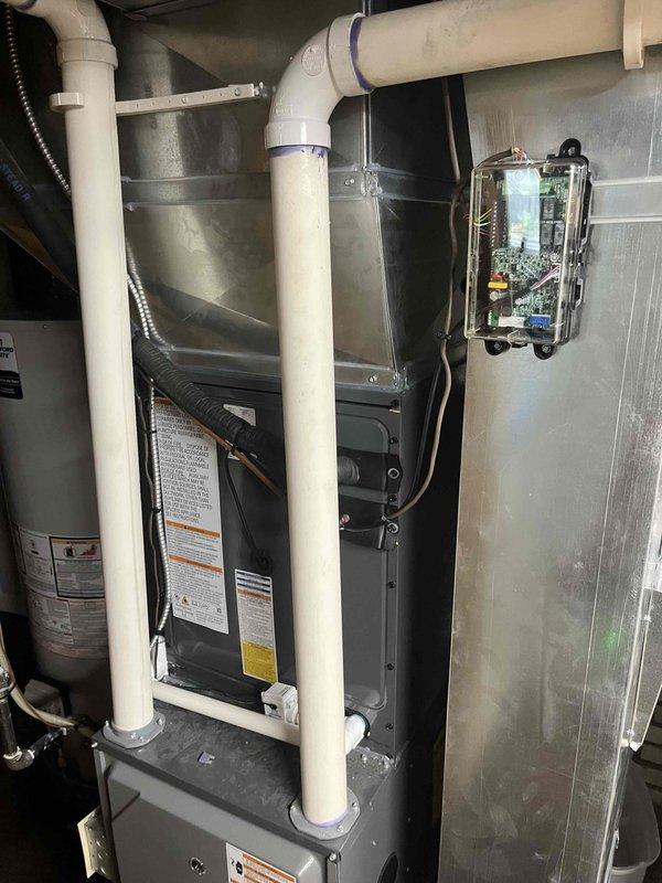 Complete HVAC system replacement performed at residential property. Removed existing air conditioning unit and installed new outdoor condensing unit on concrete pad against exterior wall with proper refrigerant line connections and electrical conduit routing. Indoor air handler unit installed in mechanical closet with new PVC condensate drain lines, proper venting, and electrical connections. All refrigerant lines insulated and secured to building exterior using appropriate mounting hardware. System charged to manufacturer specifications, electrical connections verified at disconnect boxes, and all safety controls tested for proper operation. Unit startup completed with airflow verification and thermostat calibration confirmed.