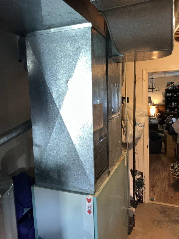 Completed comprehensive HVAC system assessment for air conditioning estimate at 6PM appointment. Documented existing galvanized metal ductwork configuration showing age-related wear and dust accumulation throughout ceiling-mounted ventilation pathways, along with installed air handler unit featuring diamond-pattern textured exterior panel and visible airflow directional indicators in utility space.