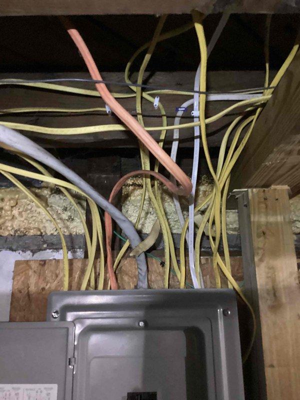 Completed on-site assessment for central air conditioning installation estimate at residential property with existing furnace system. Evaluated electrical panel capacity and wiring infrastructure in unfinished basement area, documented current electrical service configuration with multiple circuit breakers and adequate amperage for AC unit addition. Photographed attic/crawl space to assess ductwork routing options and electrical run feasibility, noting existing wire pathways through floor joists and structural framing suitable for new AC condensing unit connection.