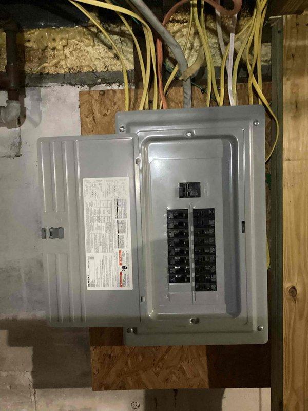 Completed on-site assessment for central air conditioning installation estimate at residential property with existing furnace system. Evaluated electrical panel capacity and wiring infrastructure in unfinished basement area, documented current electrical service configuration with multiple circuit breakers and adequate amperage for AC unit addition. Photographed attic/crawl space to assess ductwork routing options and electrical run feasibility, noting existing wire pathways through floor joists and structural framing suitable for new AC condensing unit connection.