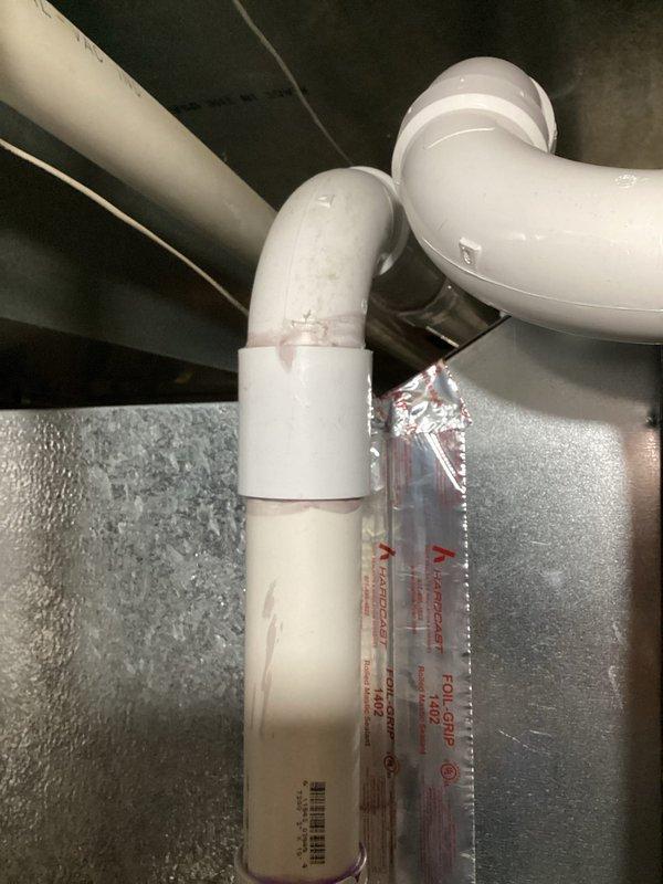 Responded to no cooling call and inspected HVAC system in attic space. Found condensate drain pan with standing water and confirmed primary drain line was properly routed through ceiling space with appropriate P-trap configuration. Verified auxiliary drain pan sensor was operational with illuminated indicators functioning correctly to alert for potential overflow conditions.