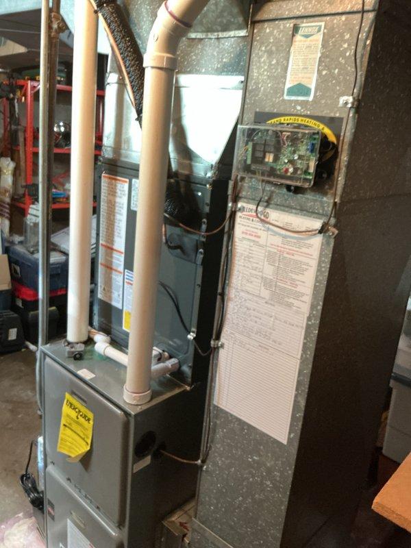 Completed full HVAC system replacement in residential basement utility room. Installed new vertical furnace unit with proper venting configuration using PVC piping for intake and exhaust. Connected condensate drainage system with pump at base of unit. Integrated air handler components and established proper ductwork connections to existing galvanized steel distribution system. Mounted control board and wiring, ensuring all electrical connections meet code requirements. Verified all safety labels and documentation affixed to equipment. System tested and confirmed operational upon completion.