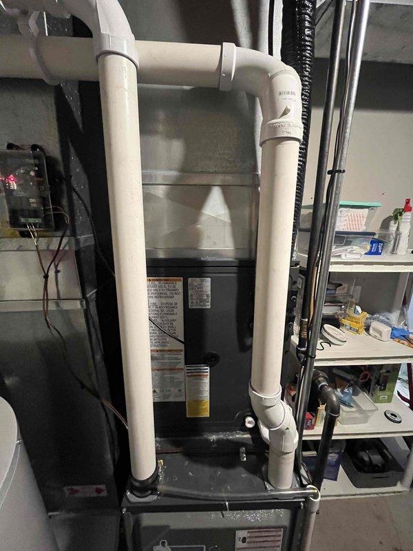 Completed full HVAC system replacement including new air handler installation in basement utility room with proper condensate drain line configuration using white PVC piping, and installed new outdoor condenser unit on gravel pad with concrete base. Removed and disposed of old cylindrical outdoor unit, established proper refrigerant lines, electrical connections via conduit, and verified all mechanical and electrical components are functioning to manufacturer specifications.