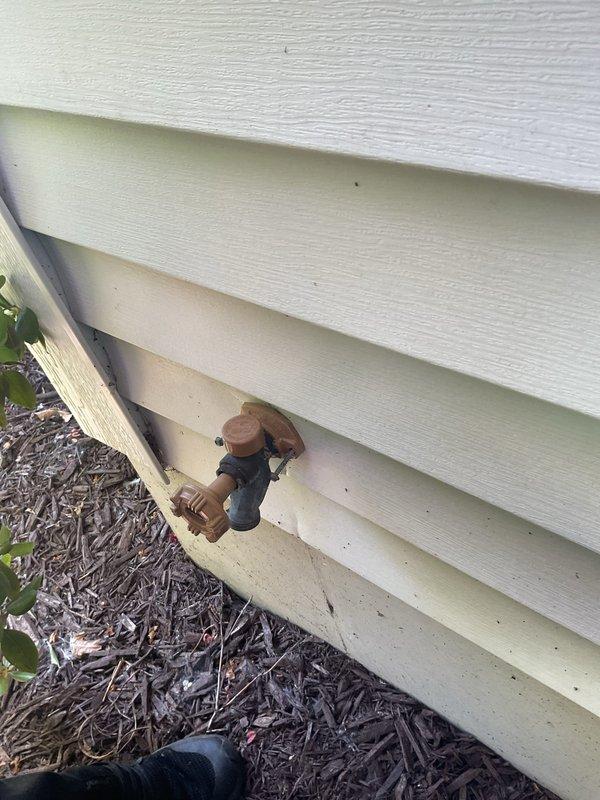 Responded to service call for two plumbing issues: outdoor faucet with continuously spinning handle and leaking pipe beneath automatic urinal flush valve in upstairs bathroom. Inspected exterior hose bib mounted on building foundation through vinyl siding—handle exhibited complete rotation indicating stripped stem or seat assembly. Accessed attic crawl space to evaluate urinal supply system; identified leak at connection point below automatic flush valve where PEX supply lines and PVC drain lines converge. Photographed both locations for documentation. Replaced faulty outdoor faucet valve stem assembly and tightened compression fittings. Repaired leaking connection at urinal valve using appropriate sealant and secured all supply line connections. Tested both repairs under full water pressure to confirm proper operation and verify no residual leaks.