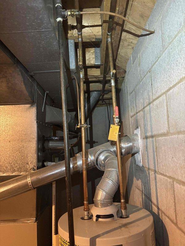 Responded to service call for air conditioning unit that would not turn on and had suspected blower motor failure on 15-20 year old system. Upon arrival, conducted diagnostic assessment of HVAC system and related mechanical equipment in utility room. Documented existing conditions of water heater, plumbing connections, ductwork, and surrounding infrastructure through photographic evidence for service records.