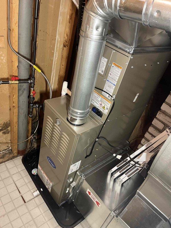 Completed full HVAC system installation including new Carrier outdoor condensing unit and indoor furnace. Positioned condenser on concrete pad adjacent to home exterior with proper clearances, connected refrigerant lines and electrical service through exterior wall penetration. Installed furnace in basement utility area with galvanized supply ductwork and 90-degree elbow configuration for proper airflow distribution. Ran electrical conduit and wiring to both units, ensuring all connections meet code requirements. Verified refrigerant charge, tested system operation across heating and cooling modes, and confirmed proper airflow and temperature differentials at supply registers.