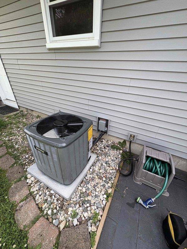 Completed full air conditioning system replacement including outdoor condensing unit and indoor air handler components. Installed new outdoor AC unit on existing concrete pad with proper leveling and secured all refrigerant line connections. Positioned unit on decorative rock bed area adjacent to home exterior with appropriate clearances maintained. Connected indoor air handler to existing furnace system in basement, integrated with ductwork infrastructure, and completed all electrical connections per manufacturer specifications. Verified proper refrigerant charge, tested system operation, and confirmed cooling performance meets specifications.