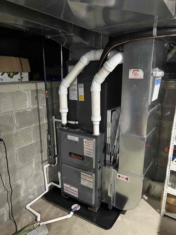 Completed full HVAC system installation including new furnace and air conditioning unit. Installed Trane outdoor condensing unit on concrete pad with proper condensate drainage via PVC piping mounted to exterior wall. Installed new furnace in basement mechanical room with associated white PVC venting routed through ceiling, copper refrigerant lines, and floor-level condensate drainage connections. All equipment positioned per manufacturer specifications, properly wired, piped, and tested for operational readiness.