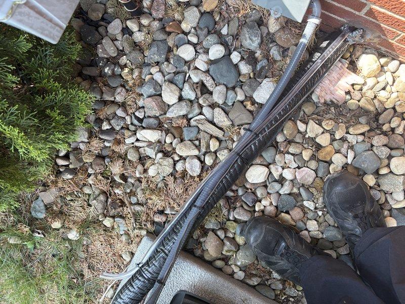 Responded to water leak complaint affecting basement area. Inspected exterior unit perimeter and foundation drainage system where water intrusion was occurring. Examined attic/ceiling space mechanical components including copper piping, ductwork, and condensate drainage lines. Documented conditions with photographs showing exterior landscaping area near unit and internal mechanical space with plumbing and HVAC systems. Identified source of water leak and completed necessary repairs to resolve basement water intrusion issue.