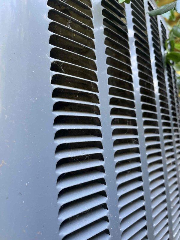 Responded to report of possible fluid leak with blue fluid present from seven-year-old EnergiAir HVAC system. Upon inspection, documented condition of exterior ventilation grilles showing normal dirt and debris accumulation but no evidence of fluid leakage, blue discoloration, or moisture present around unit or vent openings. System confirmed operational with normal cooling performance; no refrigerant leak detected during visual inspection.