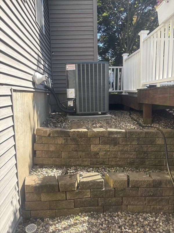 Completed full air conditioning system replacement at residential property. Installed new condensing unit on existing raised gravel platform with terraced retaining wall structure, ensuring proper elevation and drainage. Unit positioned against exterior siding with appropriate clearances maintained for airflow and serviceability. All electrical connections completed per manufacturer specifications and local code requirements. System tested and verified operational with proper refrigerant charge and airflow. Customer instructed on new system operation and maintenance requirements.