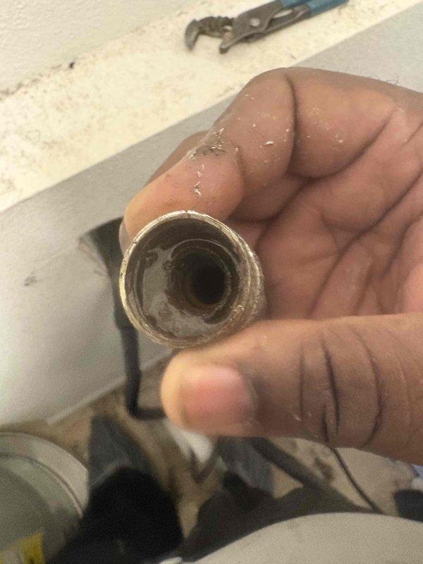 Responded to plumbing leak in bathroom of 18-year-old residential property. Upon inspection, identified deteriorated drainage pipe with significant mineral buildup and scale accumulation on interior walls. Removed compromised section of pipe, documented existing conditions with photographs, and assessed extent of sediment damage to plumbing system requiring replacement of affected components.