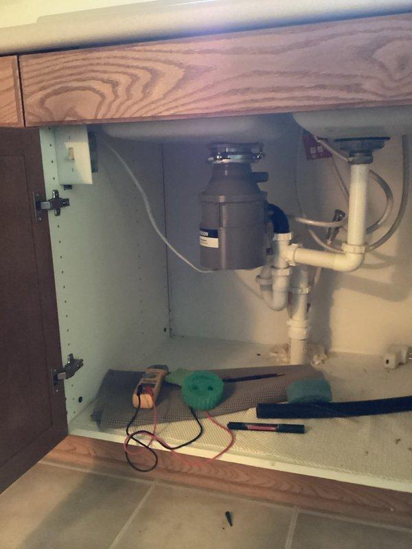 Responded to kitchen drain complaint with clogged left sink basin, non-functional garbage disposal, and foul odor. Accessed under-sink plumbing to diagnose disposal malfunction and drain blockage. Inspected P-trap configuration and disposal connections, cleared obstruction from drain line, and restored proper drainage flow to kitchen sink. Also addressed slow-draining bathtub during service visit.