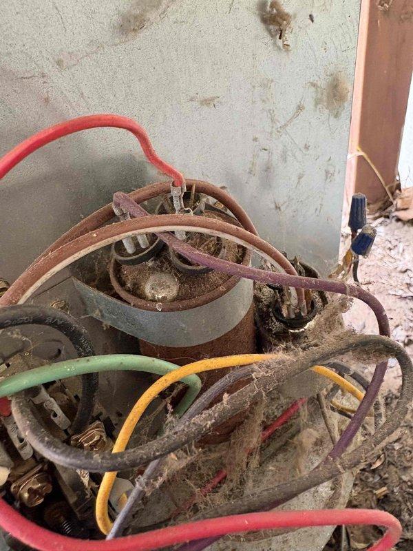 Responded to no-cooling complaint on 15-year-old air conditioning system. Upon inspection, found failed capacitor exhibiting severe corrosion and rust throughout the metal casing, indicating prolonged exposure to moisture and environmental elements. The capacitor's deteriorated condition prevented the compressor from starting, resulting in complete loss of cooling capability. Removed and replaced the failed capacitor with new component. Verified proper electrical connections and tested system operation. Unit restored to normal cooling function with compressor cycling properly and all electrical components operating within specifications.