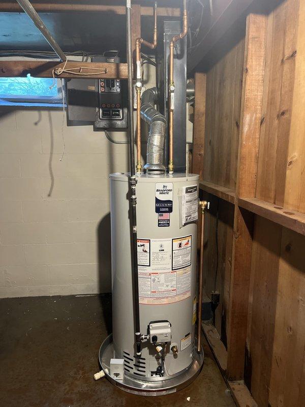 Completed installation of a 40-gallon natural gas Bradford White water heater in basement utility area. Unit was properly positioned on concrete floor, with all copper supply lines, pressure relief valve, and gas connections installed according to manufacturer specifications and local code requirements. All safety devices, shut-off valves, and plumbing connections were tested and verified operational upon completion.