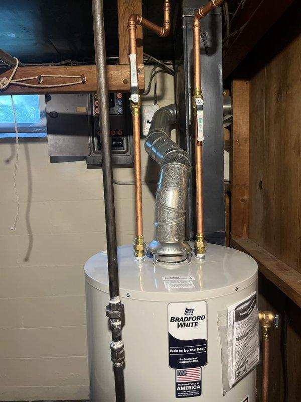 Completed installation of a 40-gallon natural gas Bradford White water heater in basement utility area. Unit was properly positioned on concrete floor, with all copper supply lines, pressure relief valve, and gas connections installed according to manufacturer specifications and local code requirements. All safety devices, shut-off valves, and plumbing connections were tested and verified operational upon completion.