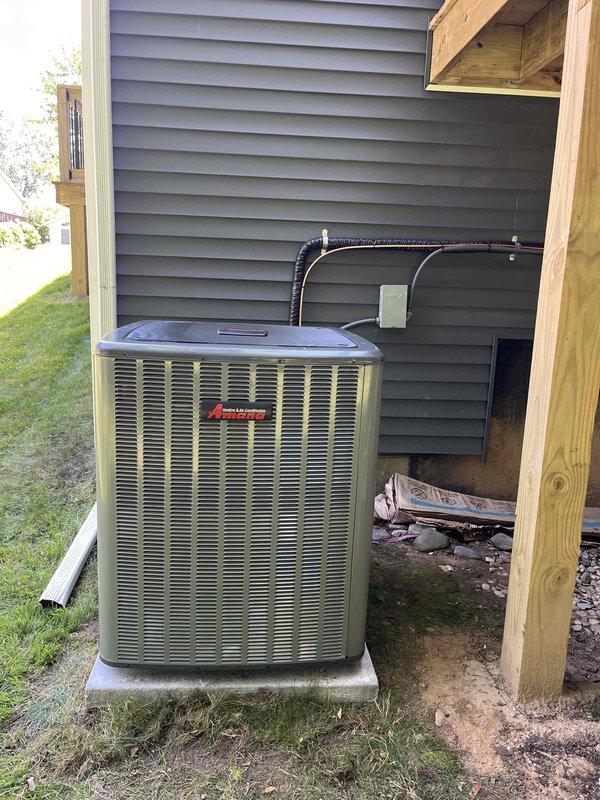 Completed full air conditioning system replacement including outdoor condenser unit and indoor furnace integration. Installed new tan-colored condenser unit on concrete pad with proper refrigerant line connections and electrical disconnect box mounted to exterior wall. Configured Trane XL 80 furnace in basement mechanical room to interface with new AC system, ensuring proper ductwork connections and airflow distribution throughout residence. All refrigerant lines properly insulated and secured to exterior siding with appropriate mounting brackets. System tested and verified operational, with financing paperwork processed and completed.