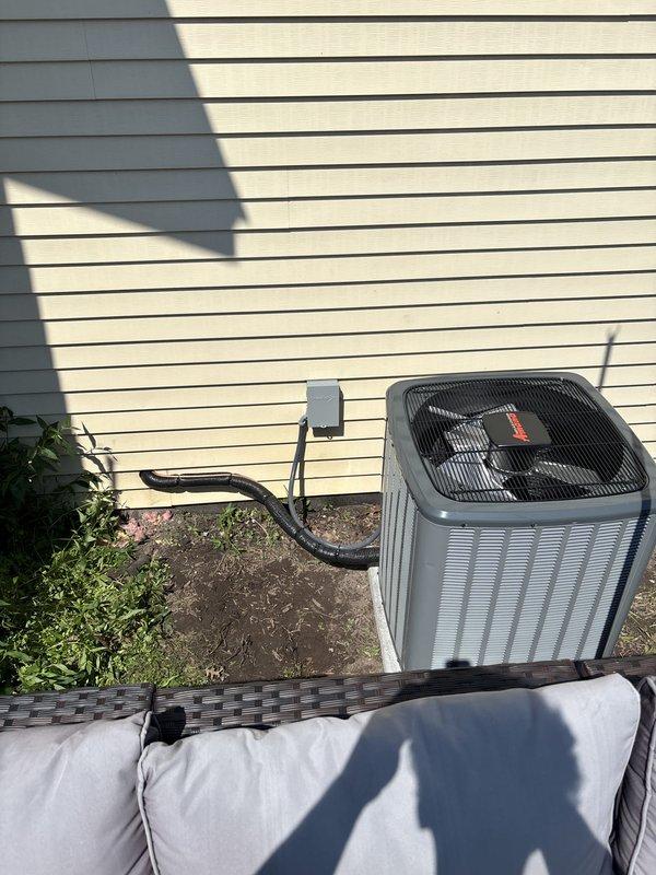 Completed full air conditioning system installation including outdoor condenser unit and indoor air handler with associated refrigerant lines, electrical connections, and condensate drainage system. Outdoor unit was positioned on prepared pad against building exterior with proper clearances, connected to dedicated electrical circuit via conduit and junction box mounted to exterior wall. Indoor air handler was installed in attic space with insulated refrigerant line set, PVC condensate drain system featuring multiple trap configurations for proper drainage, and integrated supply ductwork labeled for zoning identification. All electrical connections, refrigerant charging, and system startup procedures were completed per manufacturer specifications. System tested and verified operational.
