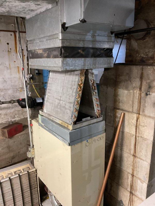 # No Cool Service Call - HVAC System Failure

Responded to service call for air conditioning unit not turning on. Upon arrival, found 25+ year old HVAC system installed in basement utility room showing extensive age-related deterioration and lack of maintenance.

## Inspection Findings

Conducted thorough visual inspection of furnace and air conditioning components. Unit casing opened to examine internal components. Heat exchanger coils displayed significant discoloration, heavy dust accumulation, and dirt buildup consistent with extended service life without regular maintenance. Flexible ductwork and copper refrigerant lines showed signs of aging. Concrete block walls in mechanical room exhibited moisture staining and deterioration, indicating poor environmental conditions for equipment operation.

## System Assessment

Evaluated electrical connections, wiring, and control systems. Examined air filter condition and airflow pathways. Assessed overall system integrity including ductwork