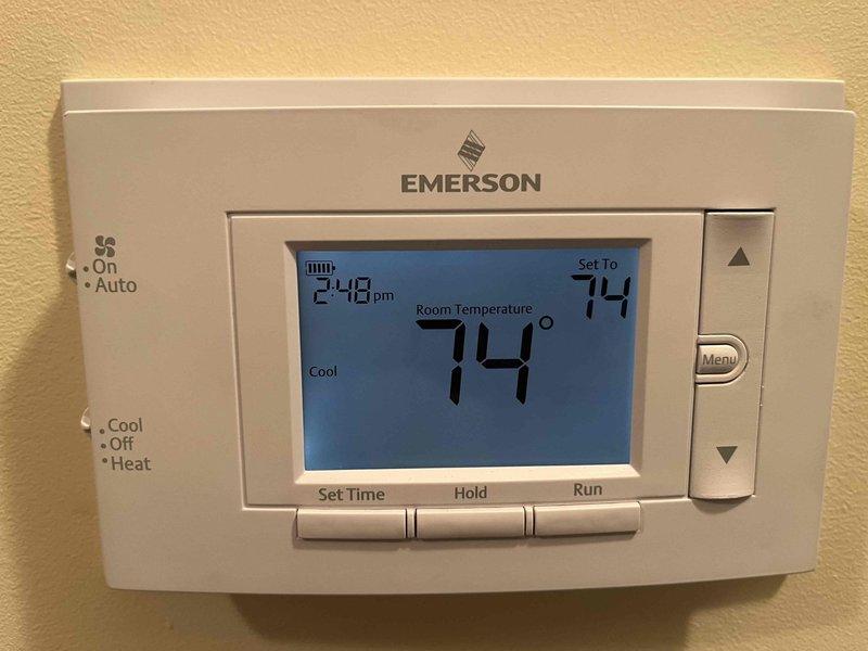 Completed annual cooling maintenance and tune-up on Carrier HVAC system. Performed comprehensive inspection of furnace unit, verified proper operation of Emerson programmable thermostat displaying 74°F set point in cooling mode, and documented system conditions with photographs. All ductwork connections, including main silver metal supply ducts and flexible black return ducts, were inspected and found secure with no visible leaks or damage.
