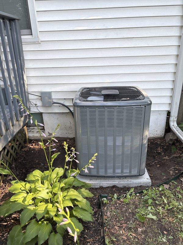 Completed full air conditioning system replacement at residential property. Installed new outdoor condenser unit on existing concrete pad against house exterior, positioned unit in landscaped area with proper clearance for airflow and serviceability. Connected refrigerant lines and electrical conduit to house per manufacturer specifications. Charged system with total of 57 ounces of refrigerant (65 ounces factory charge minus 8 ounces field adjustment) and verified proper operation of all components.