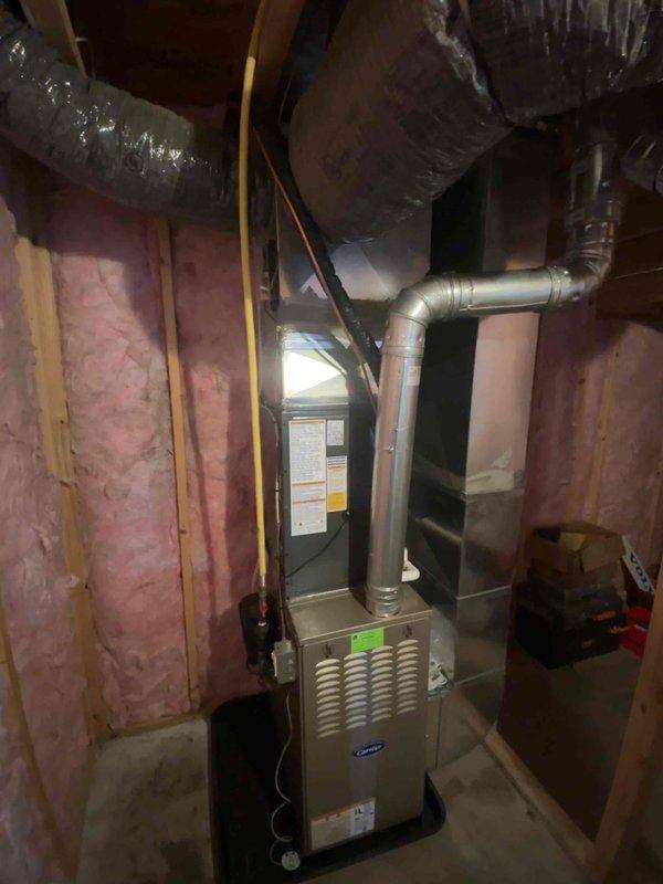 Completed full HVAC system replacement including new furnace installation in basement utility area and outdoor condensing unit. Furnace positioned with proper ductwork connections, including rigid metal supply ducts and insulated flexible return ductwork, with all electrical wiring properly routed through unfinished space. Exterior condensing unit set on concrete pad with refrigerant lines insulated and secured to building exterior, system charged and tested for proper operation.