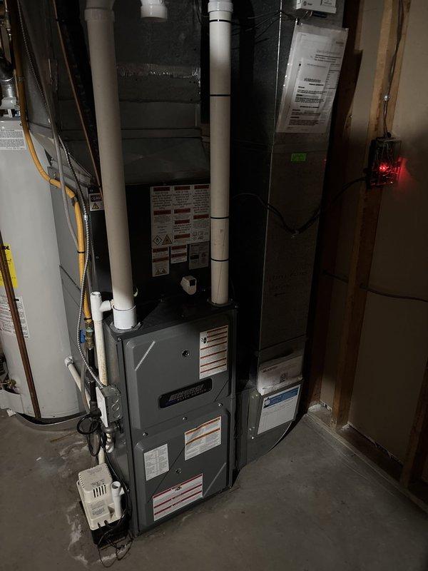 Completed full HVAC system replacement including outdoor Trane condenser unit and indoor air handler components. Installed new condensing unit on exterior concrete pad with proper electrical disconnect and conduit connections, along with refrigerant line set and condensate drainage piping. Interior installation included new air handler positioned in basement utility area with integrated furnace system, properly configured PVC venting, electrical connections, and ductwork integration to existing distribution system.