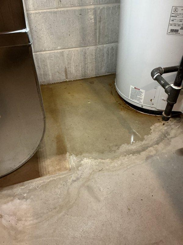 Responded to water leak complaint with puddle forming on basement floor during AC operation. Upon arrival, found 26-year-old Heil air conditioning system with clogged condensate drain line causing water to overflow onto concrete floor. Cleared blockage from condensate tube using appropriate methods to restore proper drainage flow. Verified system cooling performance remained unaffected and operational. Tested drain line for proper water discharge and confirmed no further leakage occurring. System returned to normal operation with condensate draining correctly through cleared line.