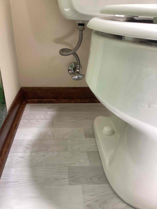 Responded to active toilet leak in main bathroom of 77-year-old home where water supply had been shut off by occupant. Upon inspection, identified leak source and assessed toilet condition along with supply line and shut-off valve connections. Evaluated whether repair was viable or full toilet replacement would be necessary given age of fixture and home. Inspected braided stainless steel supply line, chrome shut-off valve, and all connection points for signs of deterioration or failure. Documented existing installation including toilet base seal, floor flange condition, and overall fixture integrity. Verified no additional plumbing issues present in surrounding areas. Photographed toilet installation, supply line configuration, and plumbing connections for record. Provided assessment and recommendations for resolution of leak issue.