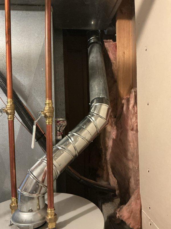 Completed installation of 40-gallon natural gas Bradford White water heater with 6-inch vent diameter and short configuration. Connected copper supply lines with brass fittings, installed flexible water connections, configured gas valve assembly and controls, and installed metallic vent pipe with proper 90-degree elbow termination through ceiling penetration. Unit installed in basement utility area on concrete floor with all safety labels visible and accessible, meeting code requirements for residential water heating systems.