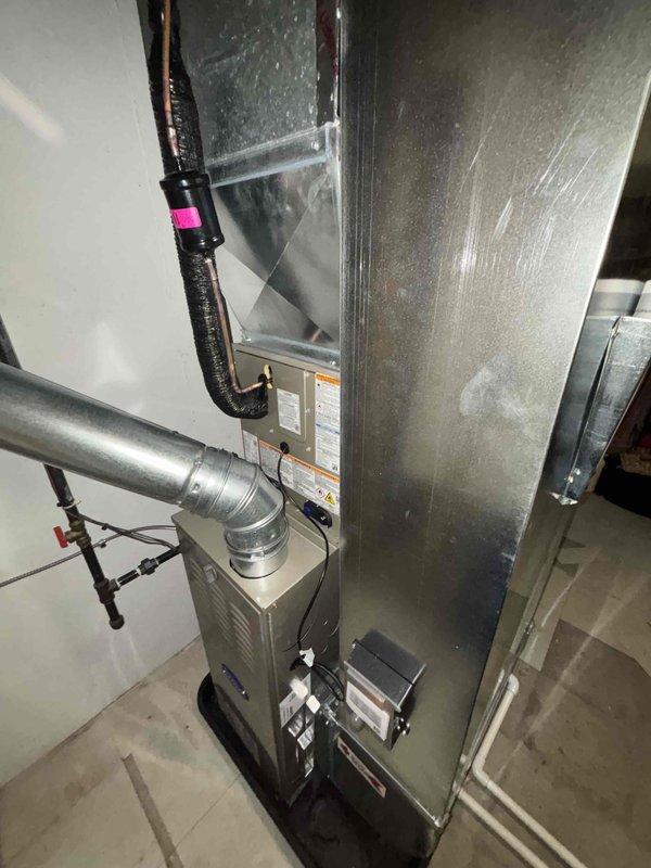 Completed full HVAC system installation including new Carrier outdoor condensing unit and indoor furnace with integrated air handler. Positioned exterior condenser on concrete pad with proper electrical disconnect and refrigerant line connections. Installed indoor equipment in basement utility area with metallic ductwork, insulated refrigerant lines, and proper plenum connections to existing duct system. All components secured, labeled, and operational upon completion.