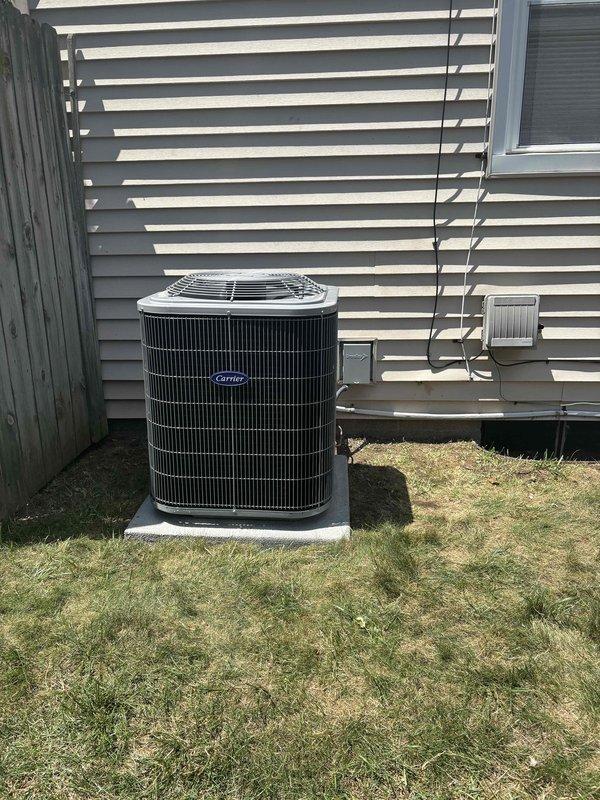 Completed full installation of residential HVAC system including new furnace and air conditioning unit. Installed Carrier brand outdoor condensing unit on concrete pad with proper clearance from structure, connected refrigerant lines and electrical conduit to exterior wall penetration. Secured all line sets and wiring along vinyl siding per manufacturer specifications. Verified proper positioning and leveling of outdoor unit on existing concrete pad. Confirmed chimney chase cover and rain cap are properly secured on masonry chimney structure with appropriate flashing at roof penetration. All components installed to code with system ready for operation.