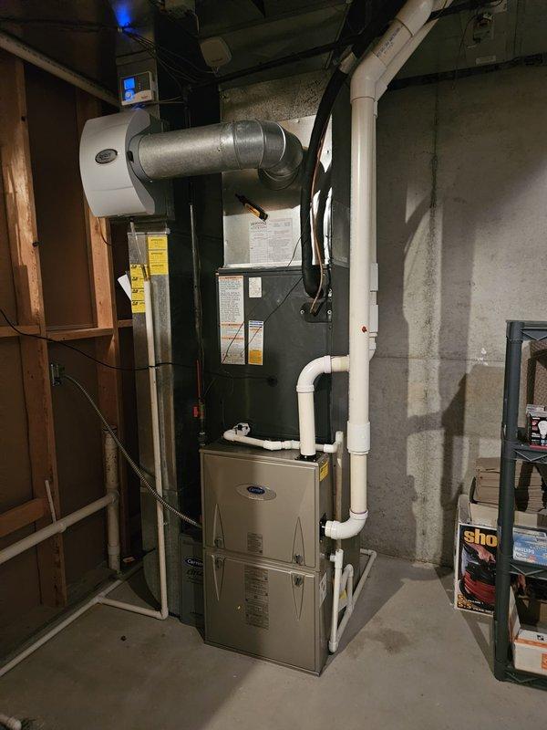 Completed full air conditioning system replacement in residential basement utility area. Removed existing AC unit and installed new condensing unit with proper refrigerant charge totaling 151 ounces (141 ounces factory charge plus 10 ounces field charge). System installation included connection to existing furnace and air handler, integration with humidifier unit, and proper routing of refrigerant lines. Verified all electrical connections, gas line connections, and PVC condensate drainage. System tested and confirmed operational with all safety controls functioning properly.