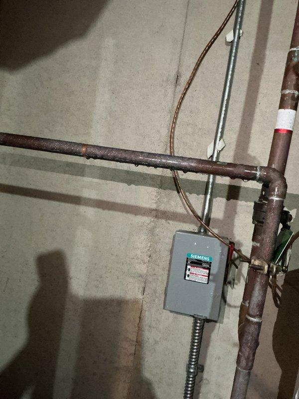 Responded to emergency service call for 20+ year old Bradford White water heater with active leak onto basement floor and inadequate water heating. Upon arrival, found extensive water damage and staining on concrete floor surrounding unit base, confirming active leak. Inspection revealed severely corroded pipes with heavy oxidation throughout the system, consistent with age of equipment. Documented existing conditions including deteriorated piping, water damage patterns, and electrical connections to Siemens panel. Unit assessed as end-of-service-life with multiple failure points requiring replacement rather than repair due to age and extent of deterioration.