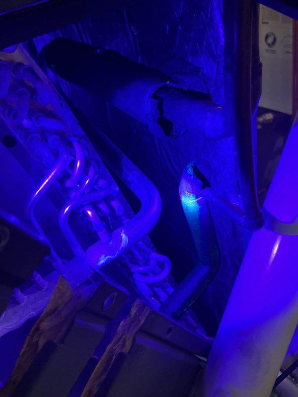 Responded to no cooling complaint on 9-month-old equipment. Performed UV leak detection on refrigerant system, inspecting copper line sets, connections, and evaporator coil assembly. UV light revealed potential leak indicators at connection points and pipe bends. Documented findings with UV photography showing fluorescent dye response on refrigerant lines and evaporator coil for further evaluation and repair recommendations.