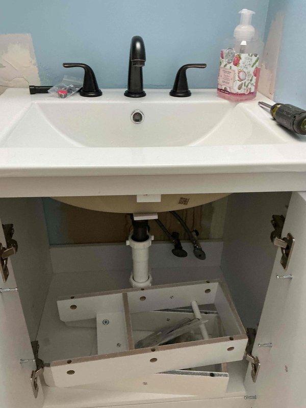 Completed bathroom vanity installation with oil-rubbed bronze three-piece faucet assembly, including supply line connections and P-trap drain configuration. Installed washing machine standpipe with proper drainage and venting in utility area, ensuring code-compliant plumbing connections for appliance hook-up.