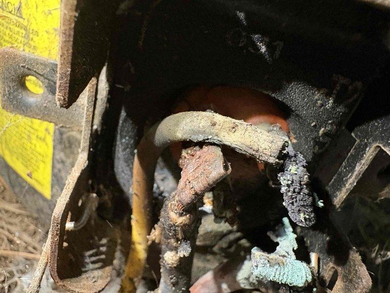 # AC Unit No Cool Service Call

Responded to service call for 12-year-old air conditioning unit that would not turn on. Upon arrival, performed complete system inspection to diagnose the no-cool condition. 

Visual inspection revealed extensive corrosion and deterioration throughout critical mechanical components. Found severely corroded shaft coupling and connecting elements showing advanced rust penetration with orange-brown discoloration and metal flaking. Observed heavy mineral buildup and crusty white deposits on multiple metal components, indicating prolonged moisture exposure. Equipment housing and mounting brackets displayed significant aging with accumulated dirt, debris, and environmental contamination.

Central mechanical junction point exhibited critical degradation with corroded circular coupling component showing deep surface cracking and material breakdown. Supporting metal pipes and tubes demonstrated reddish-brown rust coloration throughout. Equipment frame components 