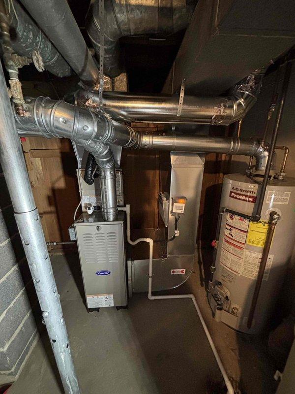 Completed full HVAC system installation including Carrier brand furnace and air conditioning condenser unit. Installed furnace in basement mechanical room with new metallic supply and return ductwork routed through ceiling joists. Positioned outdoor AC condenser unit on concrete pad adjacent to exterior wall with proper clearances, connected refrigerant lines, and installed electrical disconnect box. Established all necessary electrical connections, tested system operation, and verified proper airflow throughout ductwork. System commissioned and left in full operational condition.