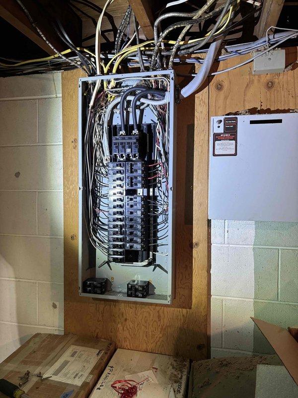 Conducted comprehensive electrical assessment of 1955-era residential property following water damage discovery during wall demolition. Evaluated existing electrical panel, circuit breaker configuration, and branch circuit wiring to determine code compliance requirements. Documented current electrical infrastructure including main service panel mounted between wall studs, circuit breaker arrangement, conductor routing, and overall system organization. Inspected wire bundling at panel entry point, verified breaker capacity distribution, and assessed condition of existing conductors. Photographed electrical panel installation, wire management, and connections to provide detailed documentation for code upgrade estimate. Identified potential areas requiring remediation to meet current National Electrical Code standards for aged residential electrical systems.